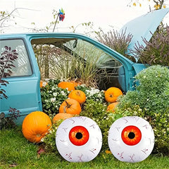 Halloween decorations with eyeball balls and pumpkins in front of a teal car.