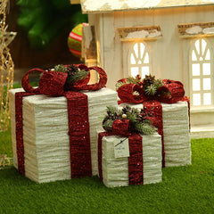 Decorative Christmas presents with red ribbons in front of a small house.