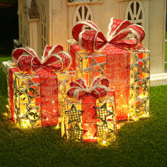 Decorative Christmas gift boxes with red ribbons and lights on grass