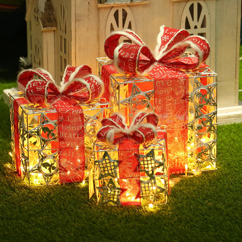 Decorative Christmas gift boxes with red ribbons and lights on grass